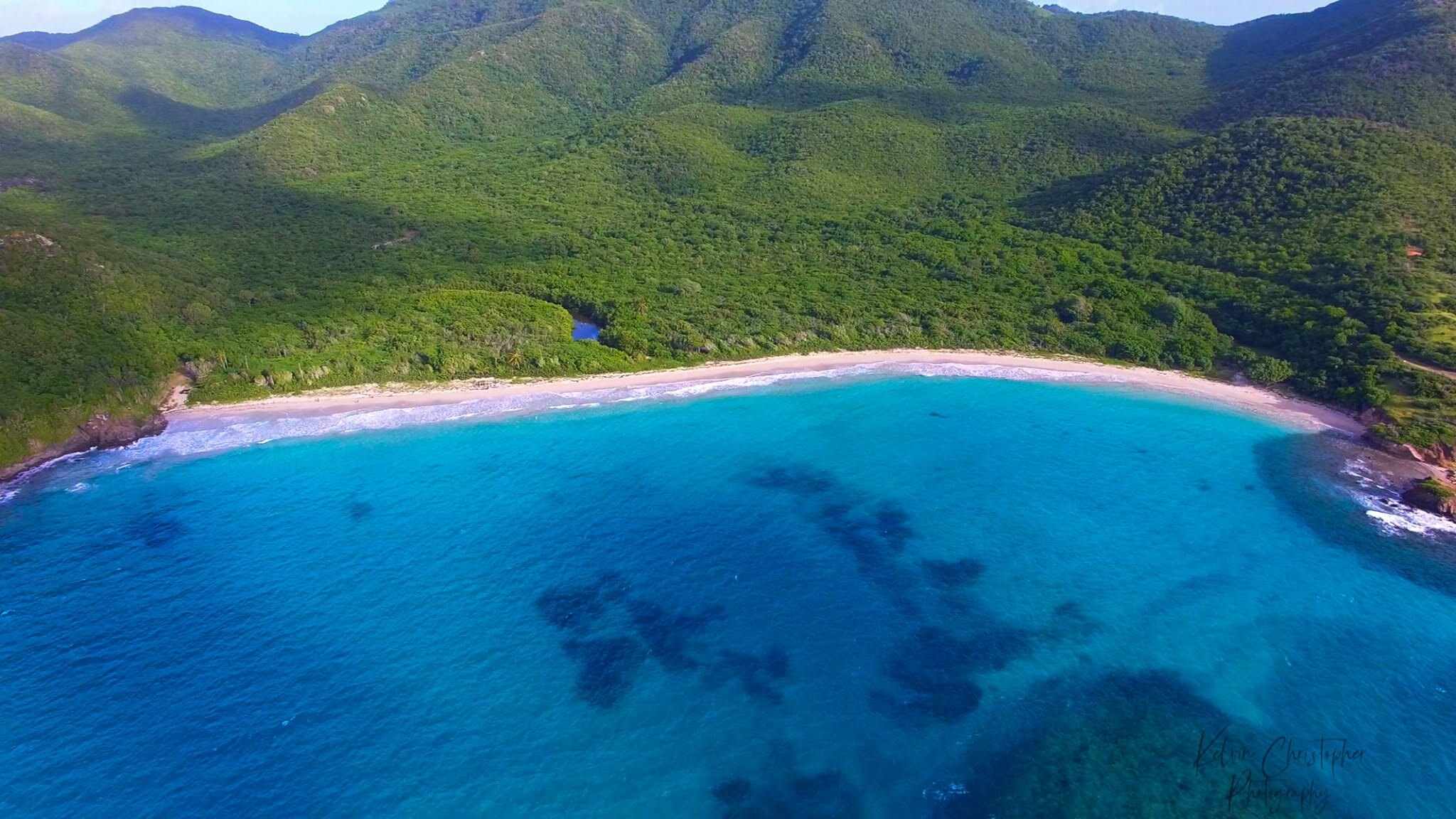 Aerial view of Antigua's green hills and bright blue coastline