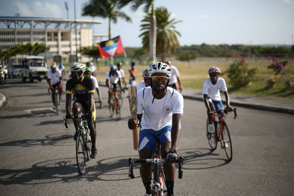 Andre Simon carrying a ceremonial torch while cycling